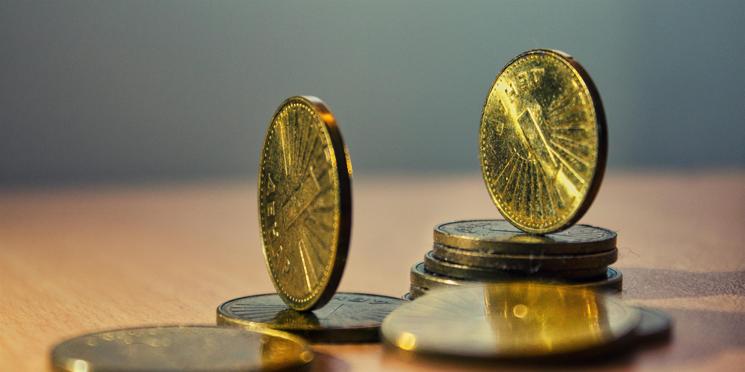 Stacks of gold coins with one coin standing upright on top of the pile
