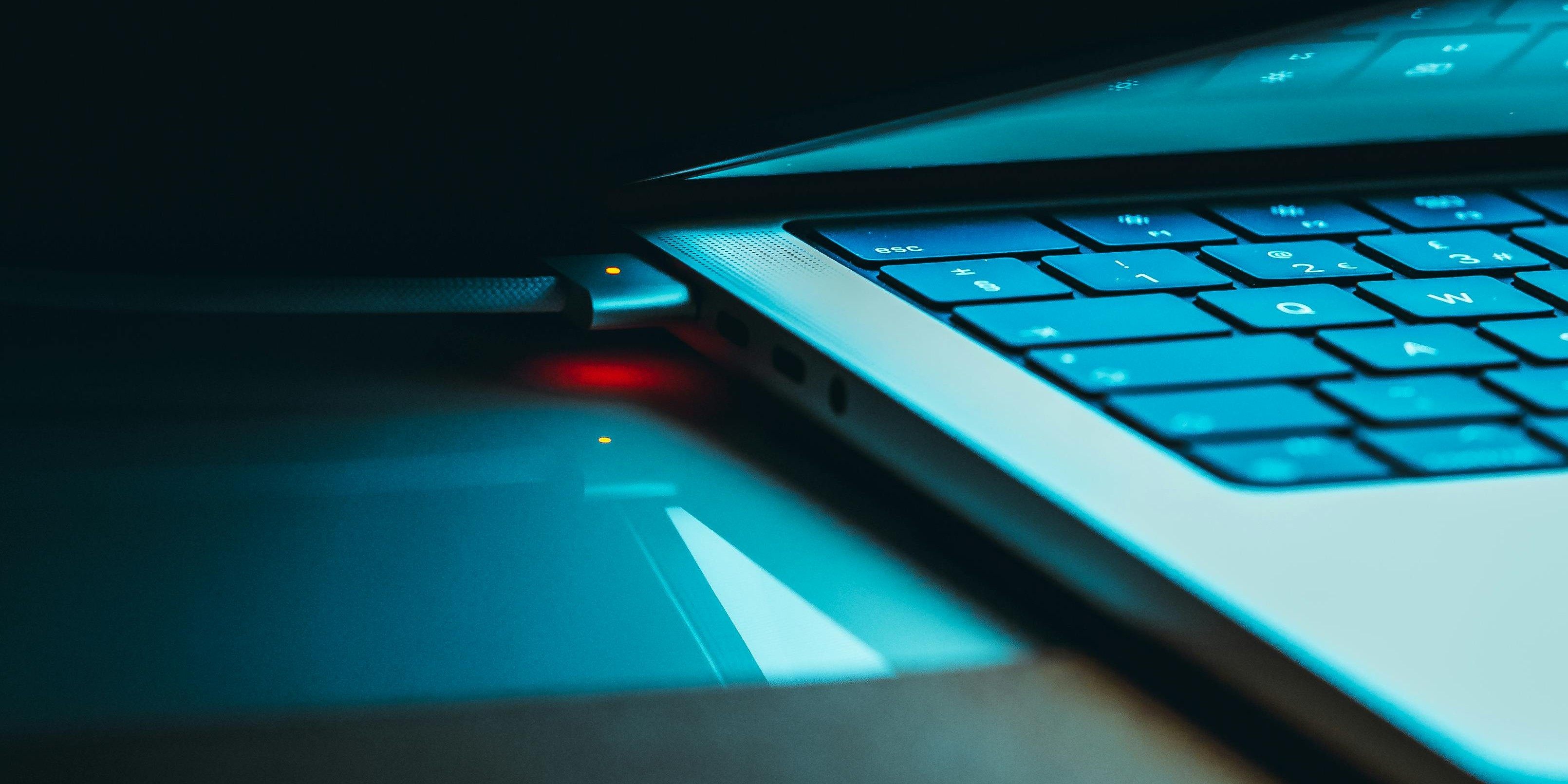 Close-up of a laptop keyboard and cooling area lit with blue light