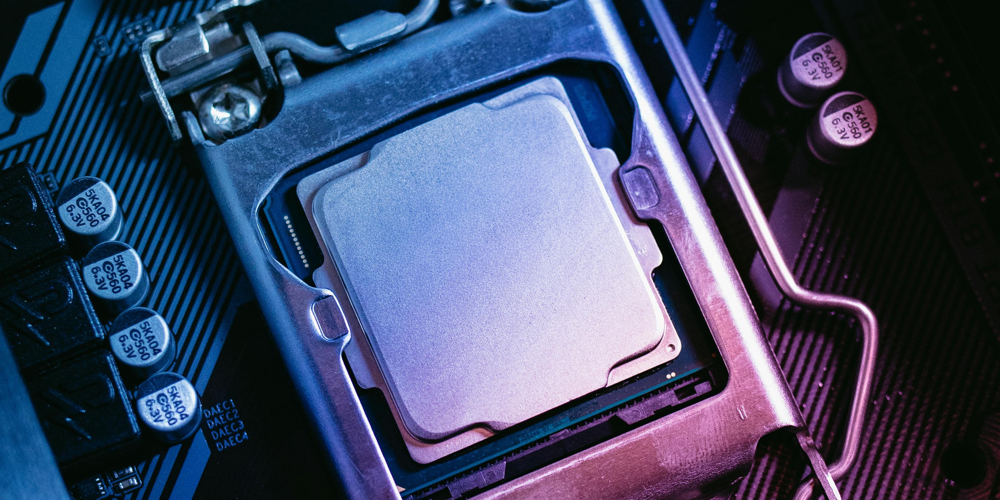 Close-up of a computer motherboard and processor socket lit in blue and purple